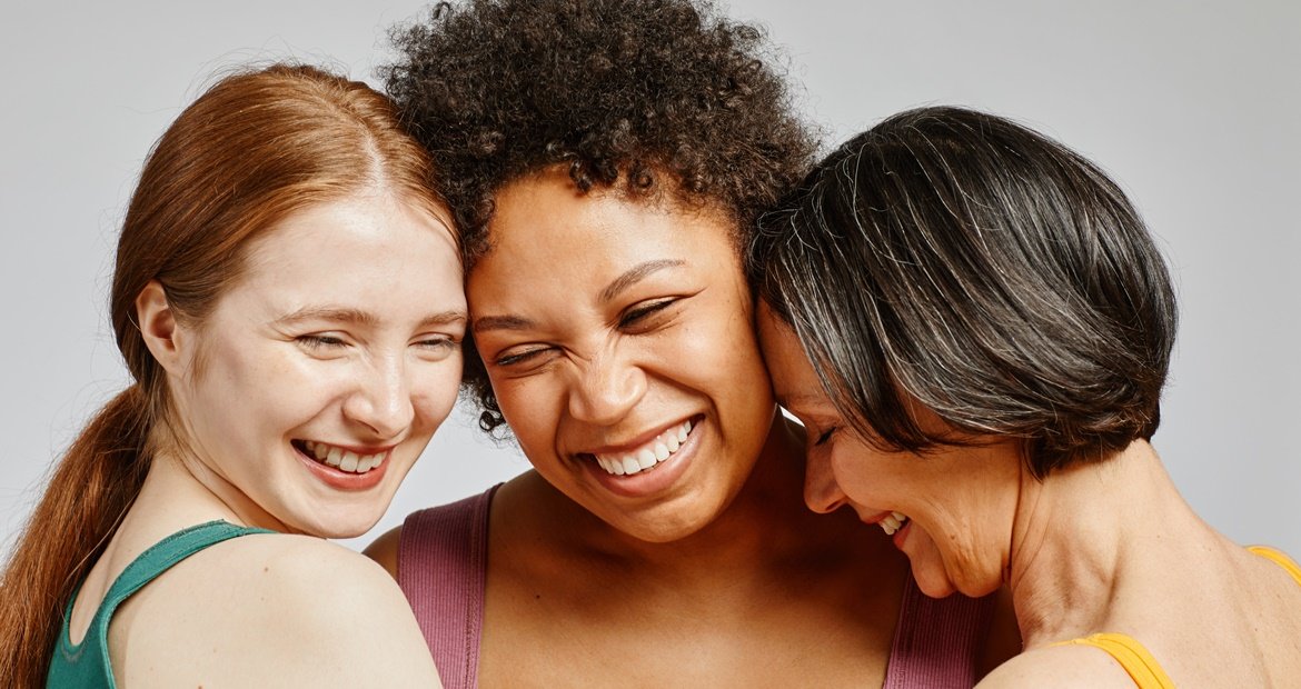 Três amigas sorrindo e se abraçando, representando a alegria de usar tinta de cabelo sem amônia para um visual saudável e radiante.