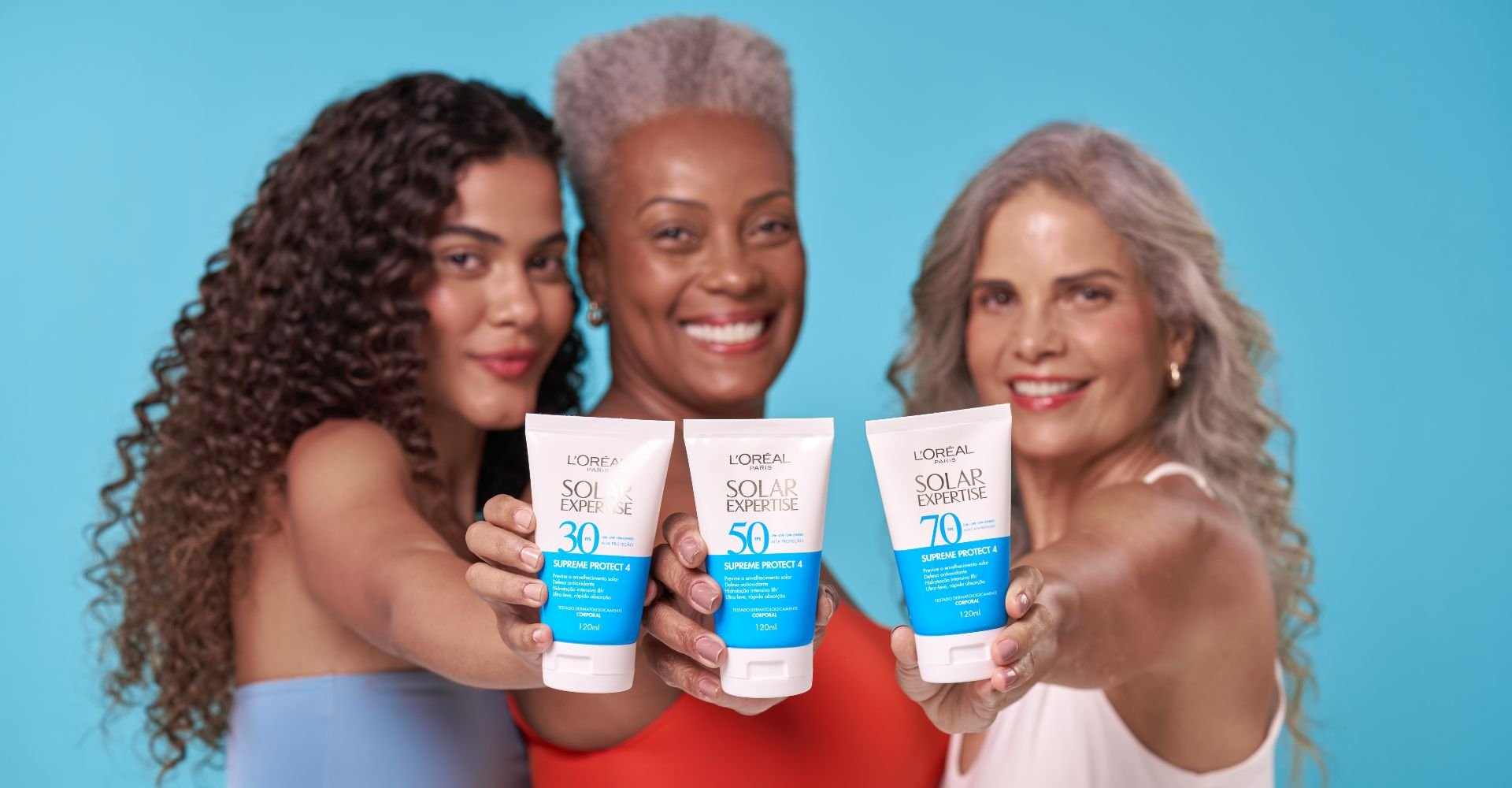 Mulheres felizes exibem o Protetor Solar Expertise Corporal de L’Oréal Paris, com alta proteção contra danos solares.