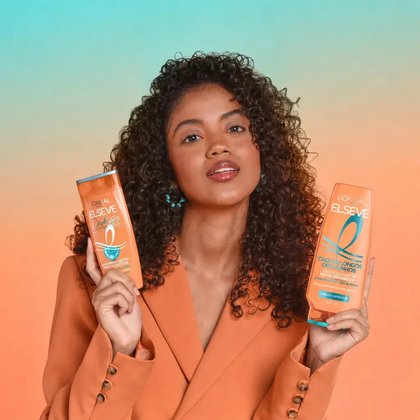 Modelo mostrando o shampoo e condicionador de Cachos Longos dos Sonhos.